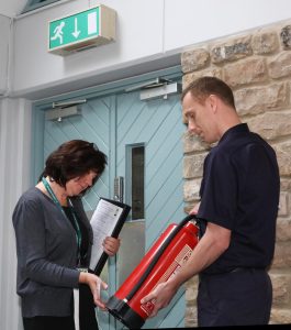 Fire Safety Officer and Business Owner checking a fire extinguisher